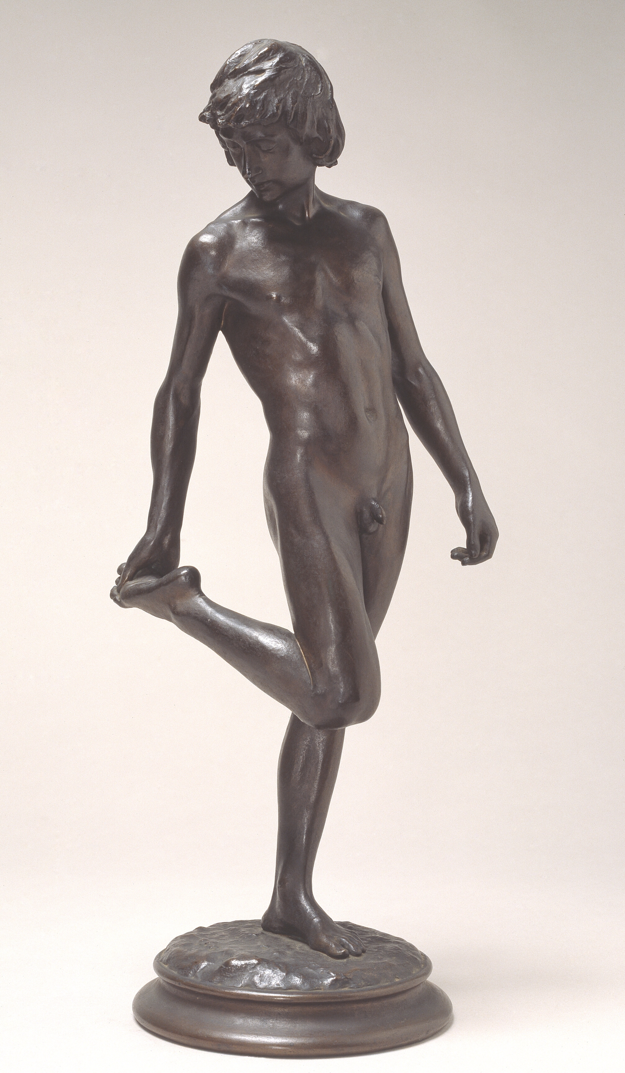 En yngling. Stående nøgen mand, der ser på sin højre fodsål