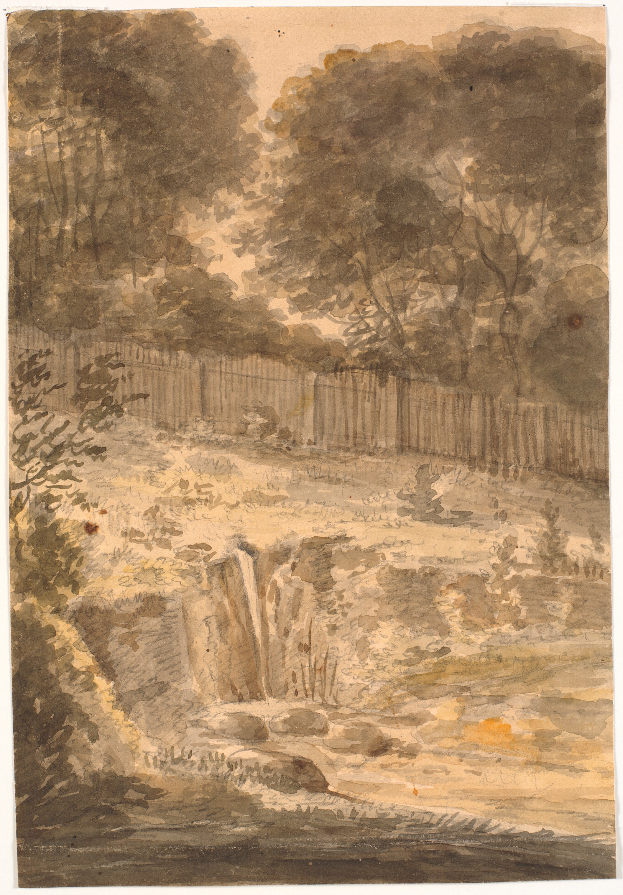 Skråning. I baggrunden træer og stakit