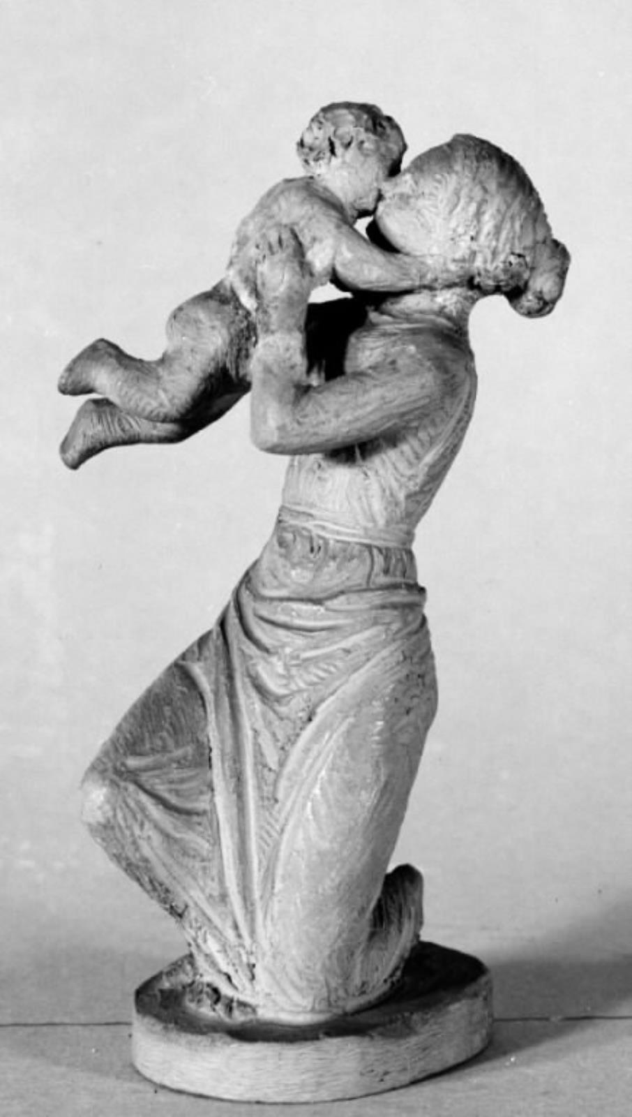 Knælende kvinde, der løfter et barn op og kysser det